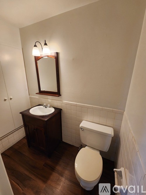 A bathroom with a toilet, sink, and mirror.