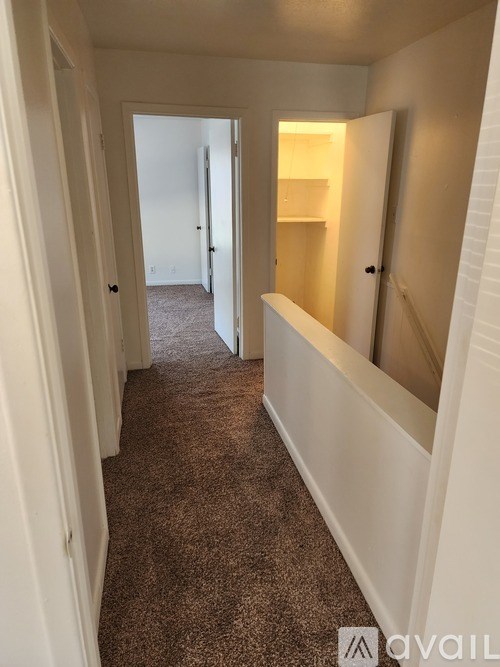 A hallway with white walls and carpeted floor.