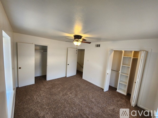 A room with a carpeted floor and a ceiling fan.