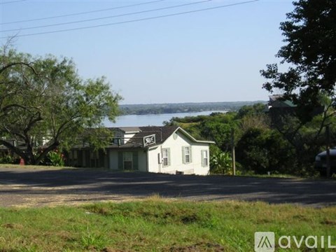 A house with a white exterior is situated in front of a body of water.