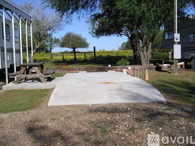 A concrete patio surrounded by a grassy area and trees.