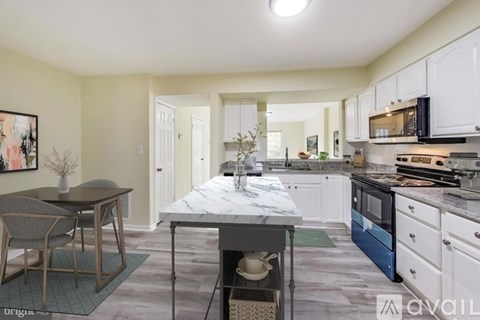 A kitchen with a table and chairs in the foreground and a dining area in the background.