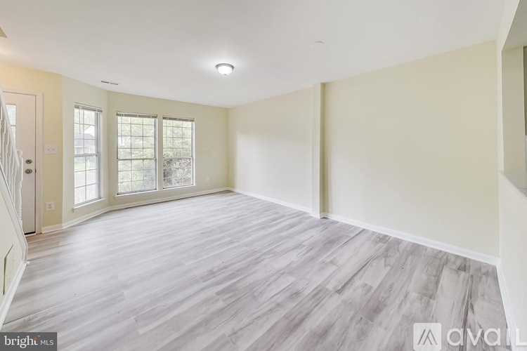 A spacious room with wooden flooring and a door leading outside.