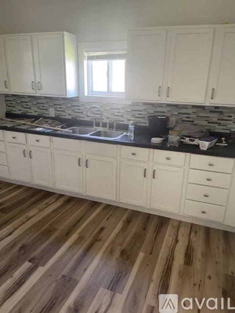 A kitchen with white cabinets and wooden floors.