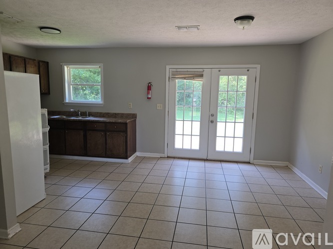 A kitchen with a white refrigerator, brown cabinets, and a tiled floor.