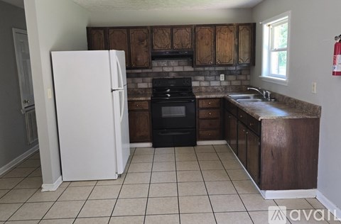 A kitchen with a white refrigerator, black oven, and brown cabinets.