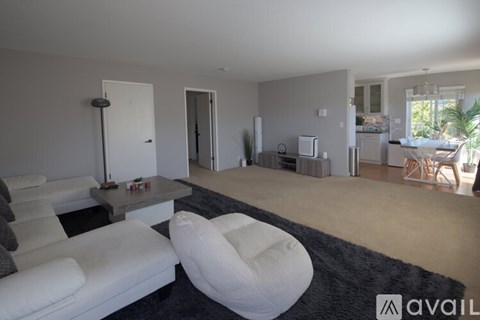 A living room with a white couch and a wooden dining table.