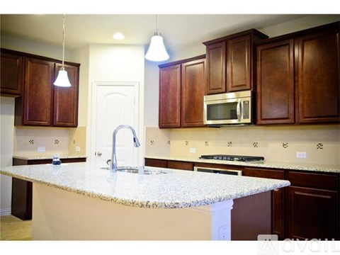 A kitchen with brown cabinets and a granite countertop.
