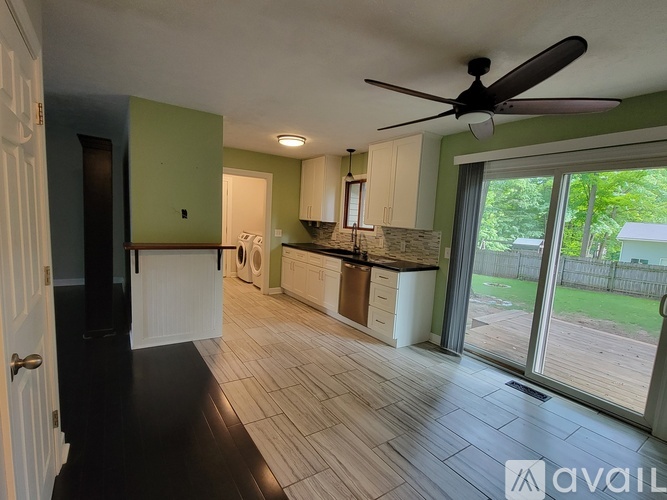 A kitchen with a fan on the ceiling and a washing machine in the corner.