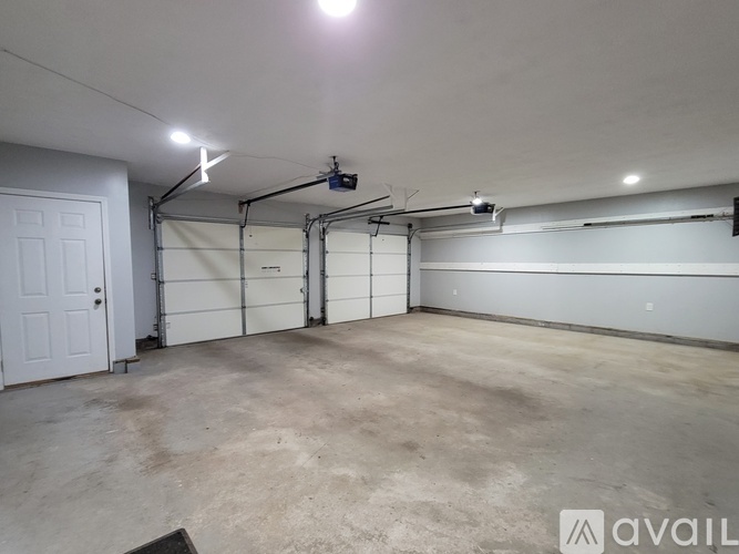 A spacious garage with a white door and a wall-mounted light fixture.