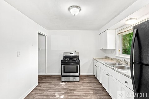 A kitchen with white cabinets and a black refrigerator.