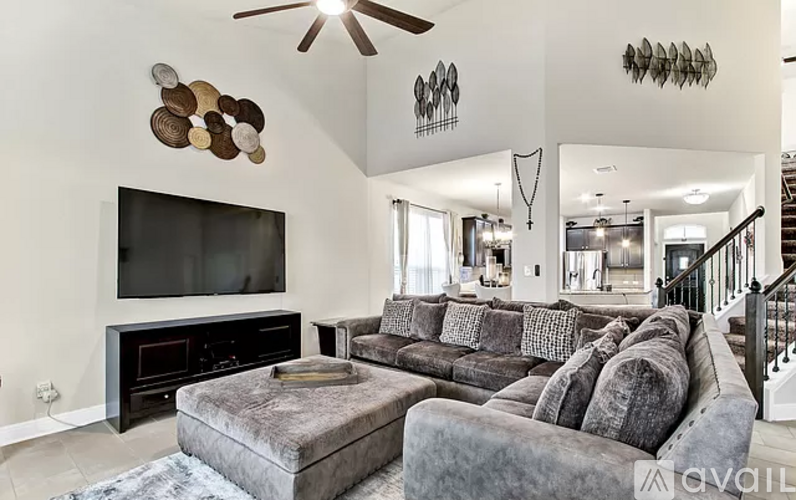 A living room with a grey couch and a black television.