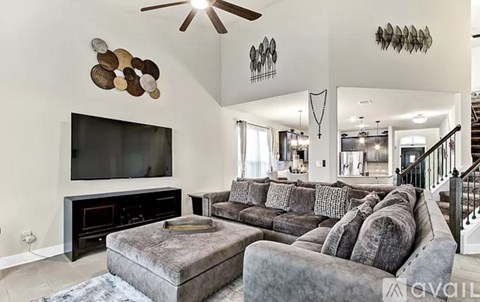 A living room with a grey couch and a black television.