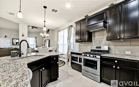 A modern kitchen with black cabinets and granite countertops.