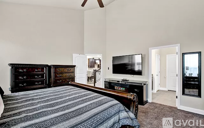 A bedroom with a bed, dresser, and television.