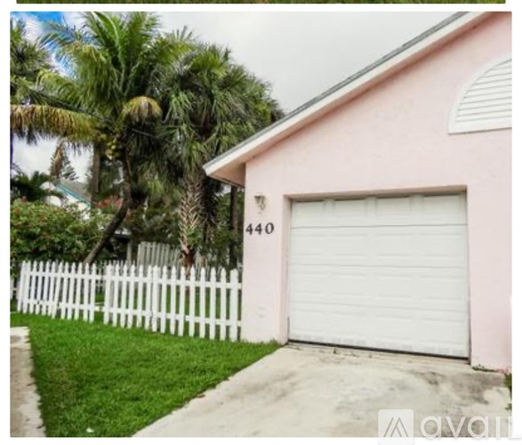A pink house with a white garage door and a white picket fence.