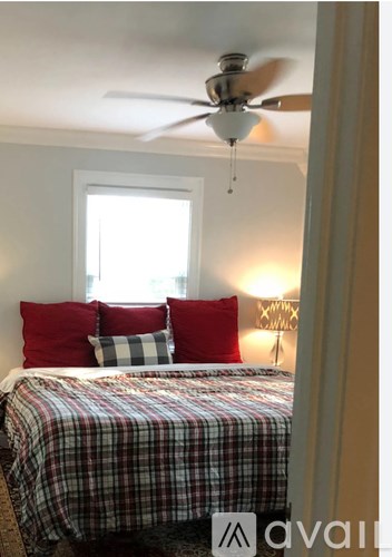 A bedroom with a bed, pillows, and a ceiling fan.