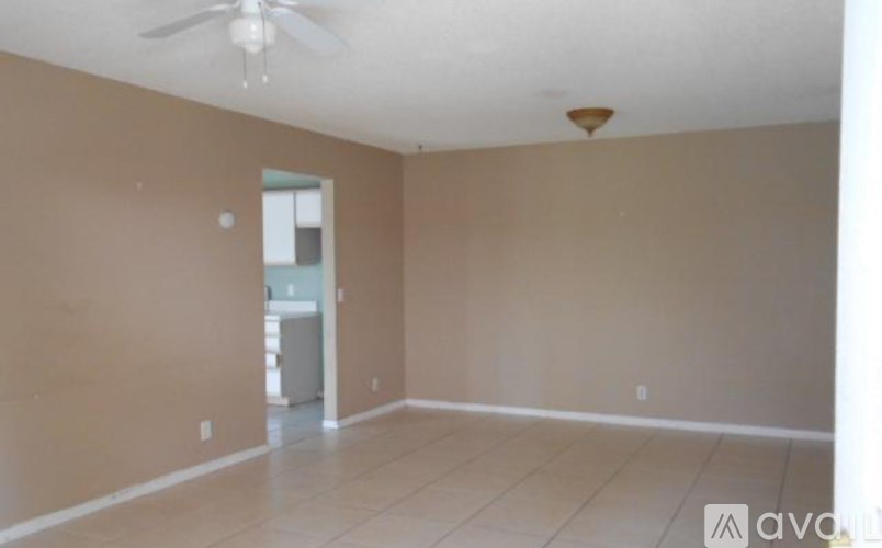 A room with beige walls and a ceiling fan.