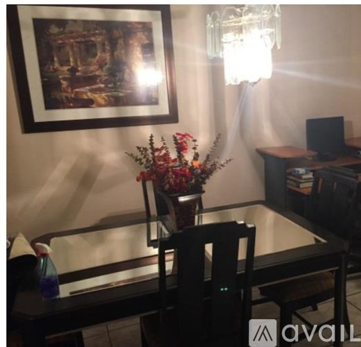 A dining room with a table, chairs, and a painting on the wall.