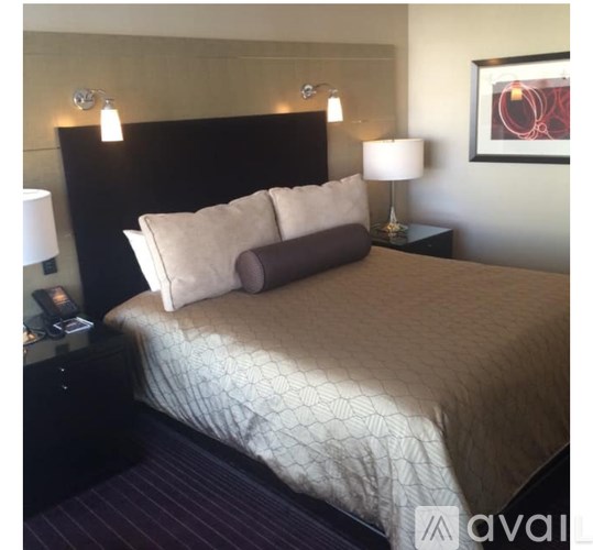 A bed with a brown headboard and a white pillow is in the image.