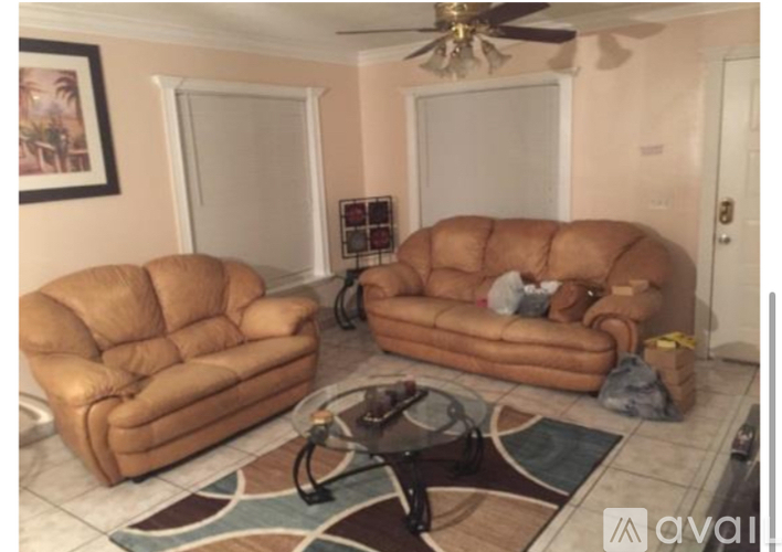 A living room with two tan couches and a rug.