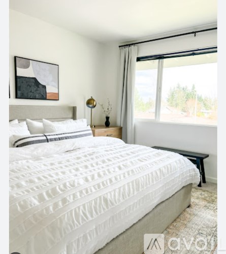A bedroom with a large bed and a painting on the wall.
