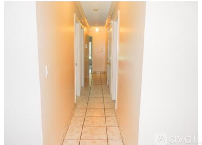 A long hallway with white walls and tiled flooring.