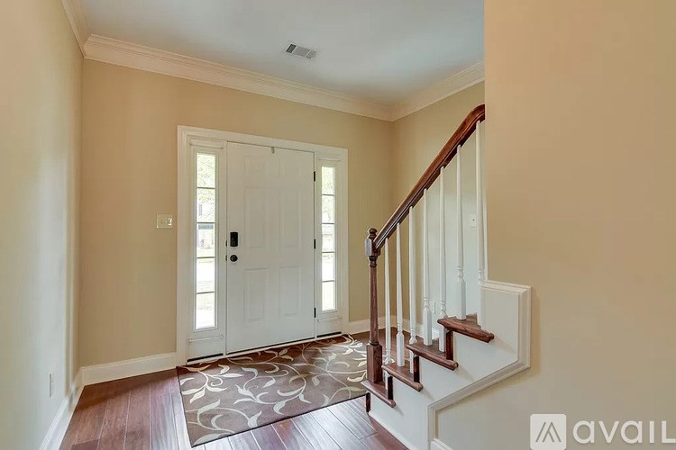A hallway with a wooden staircase and a rug on the floor.