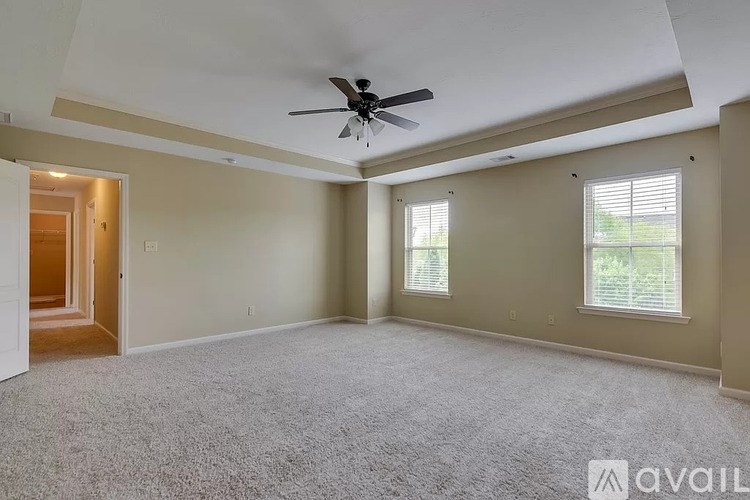 A spacious room with a ceiling fan and carpeted floor.
