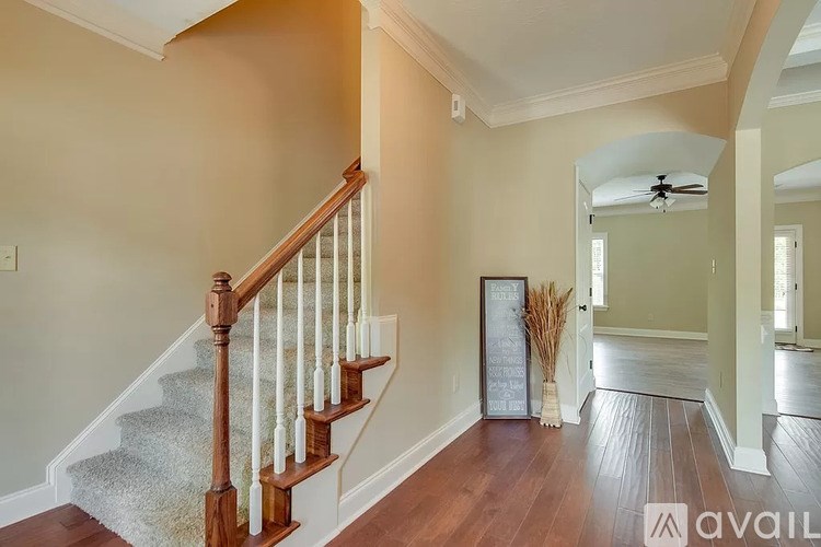 A staircase with a wooden banister and a carpeted runner leads to another room.