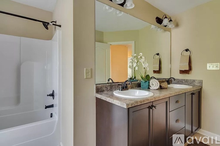 A bathroom with a white tub, a sink, and a mirror.