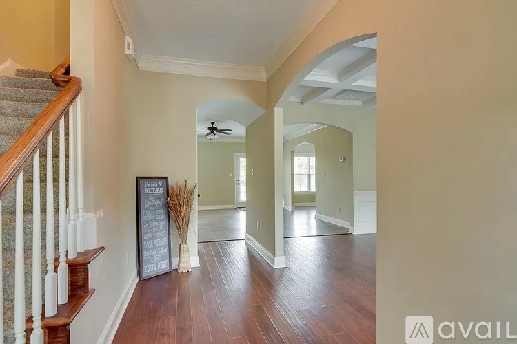 A hallway with a chalkboard sign on the wall and a staircase on the left.