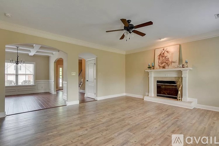 A spacious living room with a fireplace and a ceiling fan.
