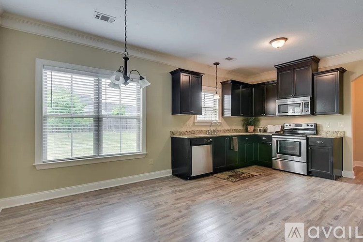 A kitchen with black cabinets and a wooden floor.