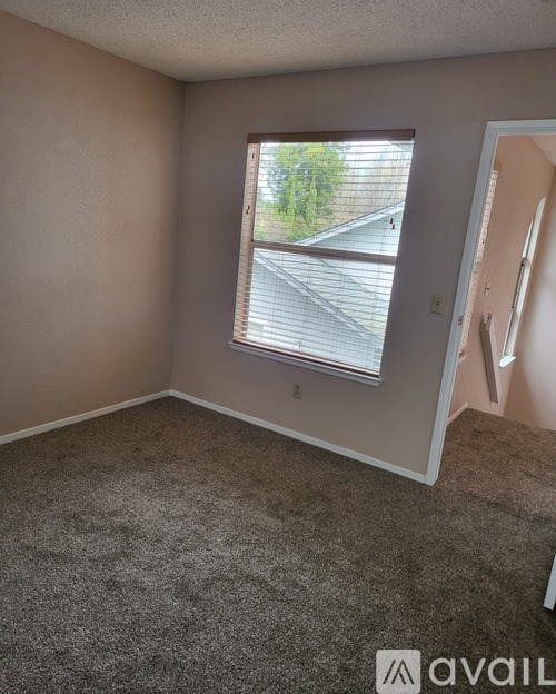 A room with a carpeted floor and a window with blinds.
