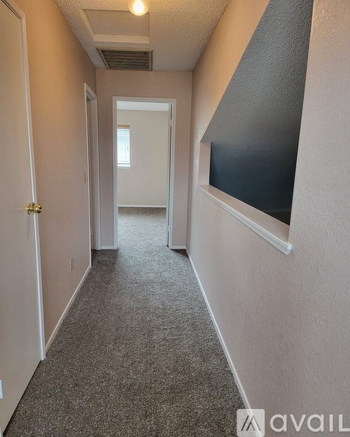 A long, narrow hallway with a carpeted floor and white walls.