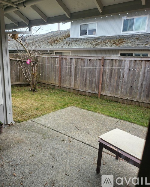 A patio with a bench and a tree.