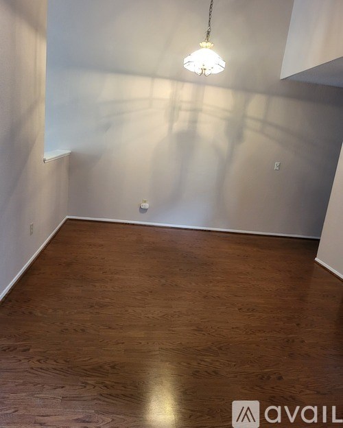 A room with wooden flooring and a hanging light fixture.