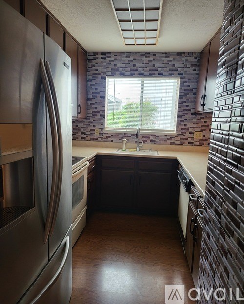 A kitchen with a stainless steel refrigerator and a brick wall backsplash.