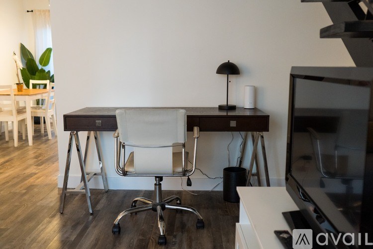 A white chair is in front of a desk with a black lamp on it.