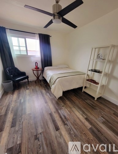 A room with a bed, chair, and shelf.