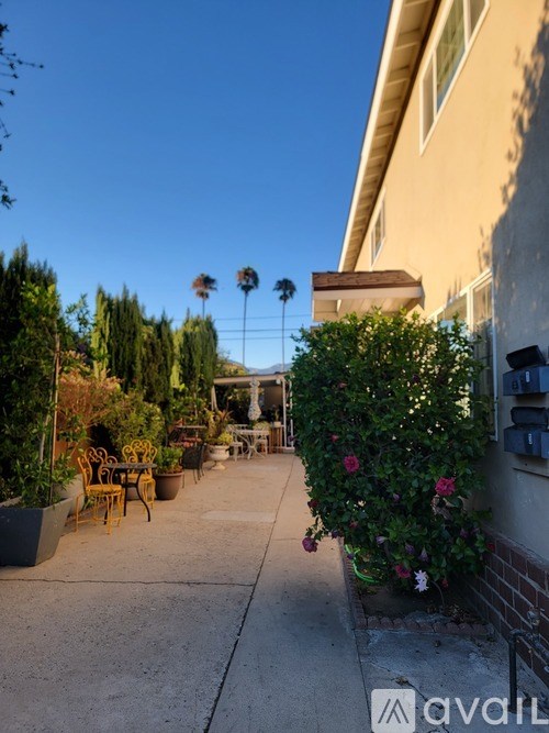 A patio with a table and chairs surrounded by greenery.