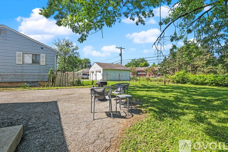A backyard with a table and chairs under a tree.