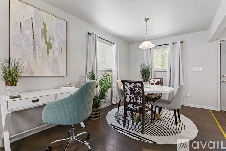 A room with a desk, chairs, and a painting on the wall.