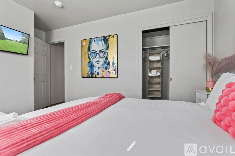 A bedroom with a large bed and a painting on the wall.