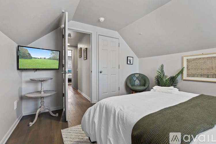 A bedroom with a bed, a television, and a plant.