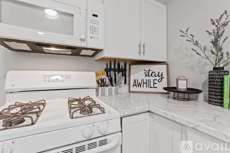 A white stove with a sign that says "stay awhile" on the counter.
