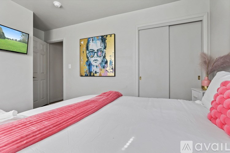 A bedroom with a large bed and a painting on the wall.