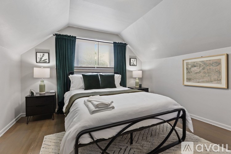 A bedroom with a large bed and a window with green curtains.