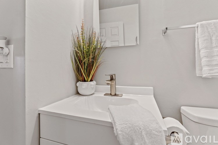 A white bathroom with a white sink and a white towel hanging on the side.